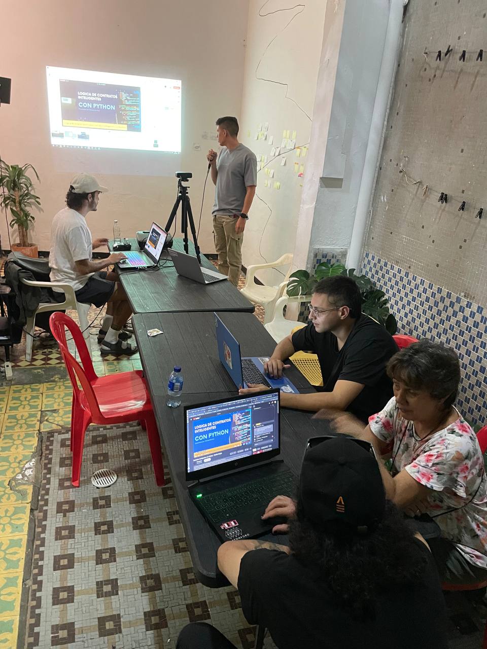 Participantes de un taller de Web3wasi aprendiendo en comunidad con computadores y una proyección en Platohedro